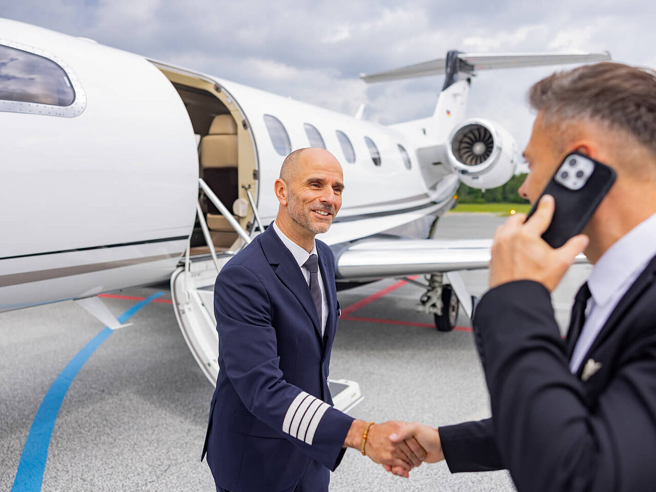 Das Bild zeigt ein kleines Passagierflugzeug am Flughafen Hof-Plauen für Charterflüge. Im Vordergrund ist der Pilot mit einem Geschäftsmann, welcher telefoniert zu sehen