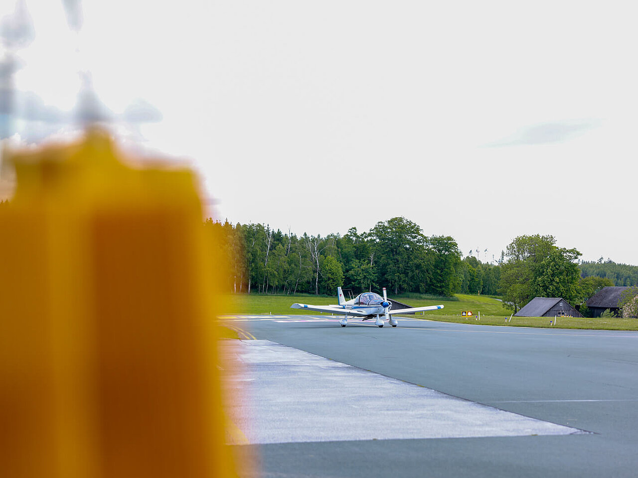 Das Bild zeigt den Flughafen Hof-Plauen mit einem kleinen Sportflugzeug im Hintergrund