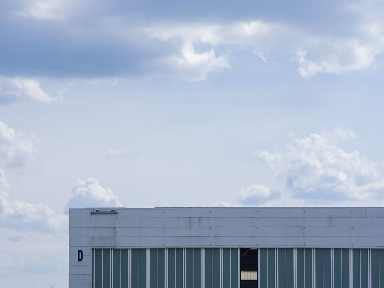 Das Bild zeigt den Hangar des Flughafen Hof-Plauen mit einem kleinen Sportflugzeug davor